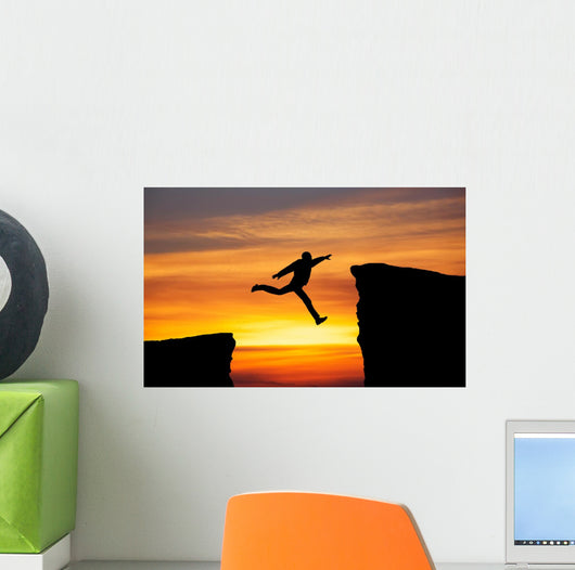 Man jumping across the gap from one rock to cling to the other. Wall Decal