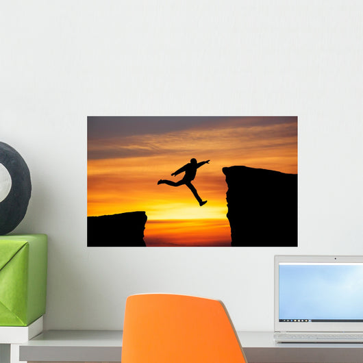 Man jumping across the gap from one rock to cling to the other. Wall Decal