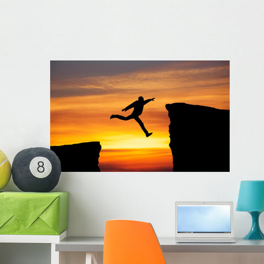 Man jumping across the gap from one rock to cling to the other. Wall Decal