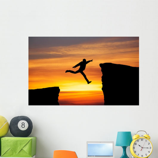 Man jumping across the gap from one rock to cling to the other. Wall Decal