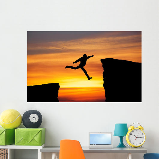 Man jumping across the gap from one rock to cling to the other. Wall Decal