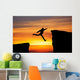 Man jumping across the gap from one rock to cling to the other. Wall Decal