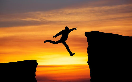 Man jumping across the gap from one rock to cling to the other. Wall Decal