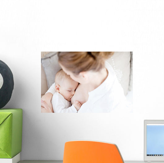 Young mother breastfeeding the newborm baby - indoors Wall Decal