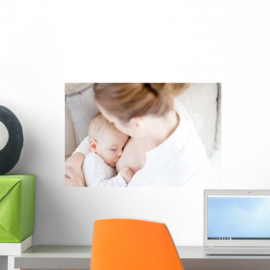 Young mother breastfeeding the newborm baby - indoors Wall Decal
