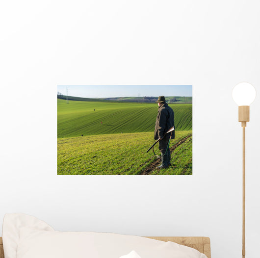 Gamekeeper walks over field. Wall Decal