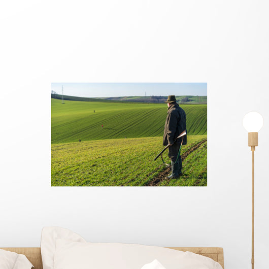 Gamekeeper walks over field. Wall Decal