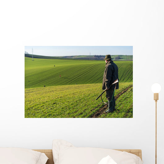 Gamekeeper walks over field. Wall Decal