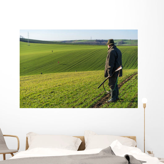 Gamekeeper walks over field. Wall Decal