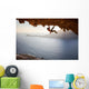 Rock climber climbing along roof in cave at sunset Wall Decal