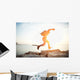 brave man running over rocks near ocean in beautiful sunset Wall Decal
