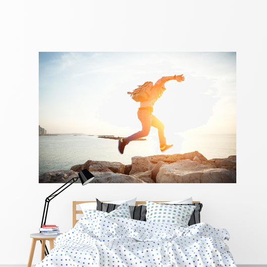 brave man running over rocks near ocean in beautiful sunset Wall Decal