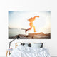 brave man running over rocks near ocean in beautiful sunset Wall Decal