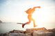 brave man running over rocks near ocean in beautiful sunset Wall Decal