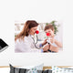 Smiling doctor examining success child with finger up Wall Decal