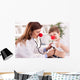 Smiling doctor examining success child with finger up Wall Decal