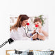 Smiling doctor examining success child with finger up Wall Decal