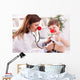 Smiling doctor examining success child with finger up Wall Decal