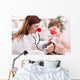 Smiling doctor examining success child with finger up Wall Decal