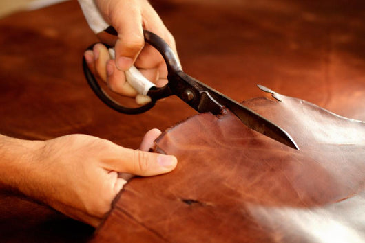 Tailor cutting animal skins at textile factory Wall Decal