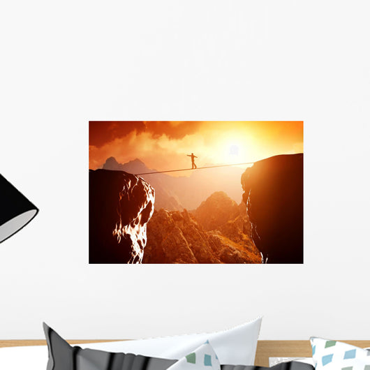 Man walking and balancing on rope over precipice in mountains Wall Decal