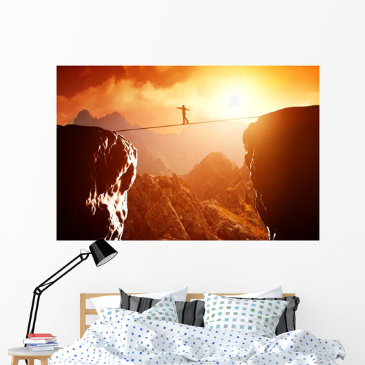 Man walking and balancing on rope over precipice in mountains Wall Decal