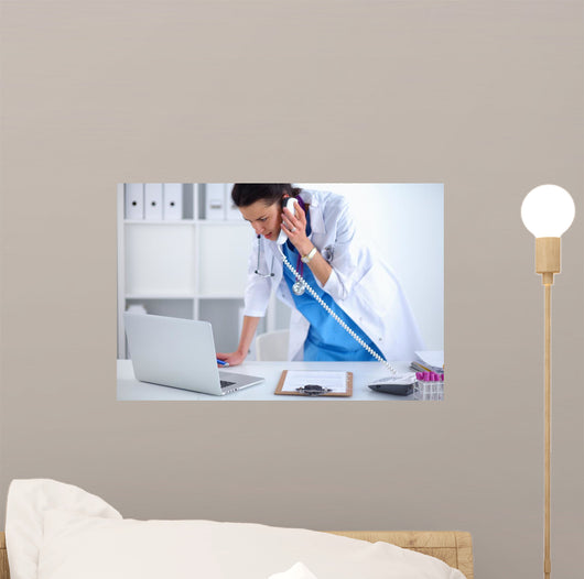 Young Woman Doctor In White Coat At Computer Using Phone Wall Decal