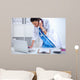 Young woman doctor in white coat at computer using phone Wall Decal