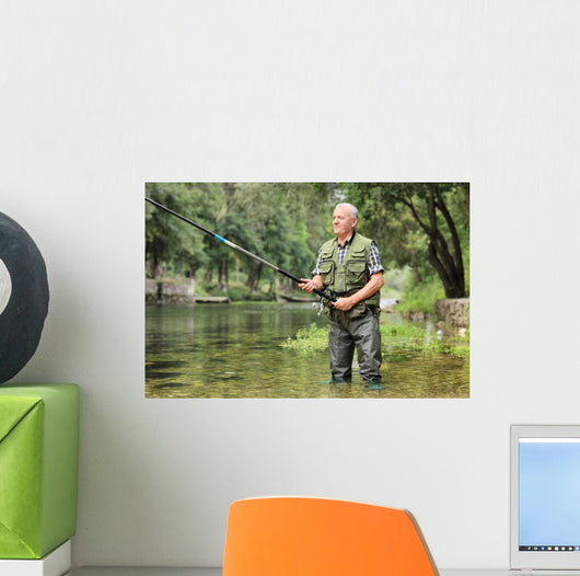 Cheerful mature fisherman fishing in a river Wall Decal