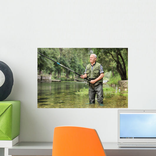 Cheerful mature fisherman fishing in a river Wall Decal