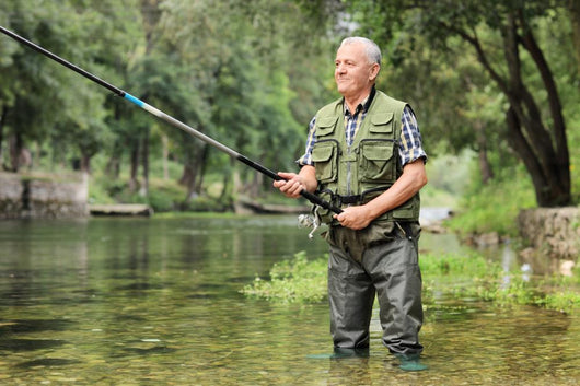 Cheerful mature fisherman fishing in a river Wall Decal