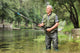 Cheerful mature fisherman fishing in a river Wall Decal