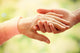 Old and young holding hands on light background, closeup Wall Decal
