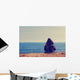 Girl sitting on a meadow with a beautiful sea/ocean view. Wall Decal