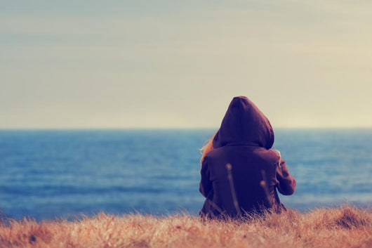 Girl sitting on a meadow with a beautiful sea/ocean view. Wall Decal