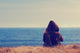 Girl sitting on a meadow with a beautiful sea/ocean view. Wall Decal