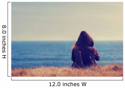 Girl sitting on a meadow with a beautiful sea/ocean view. Wall Decal