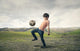 Boy playing football in the countryside Wall Decal