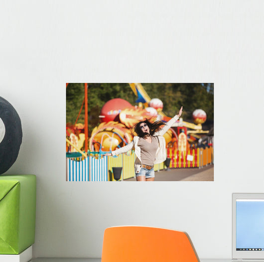 Amusement park rides. A young woman is happy and jumps. Wall Mural