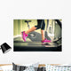 Fitness girl running on treadmill. With muscular legs in gym. Wall Mural