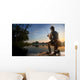 Young man fishing at misty sunrise Wall Mural