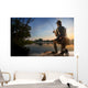 Young man fishing at misty sunrise Wall Mural