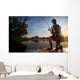 Young man fishing at misty sunrise Wall Mural