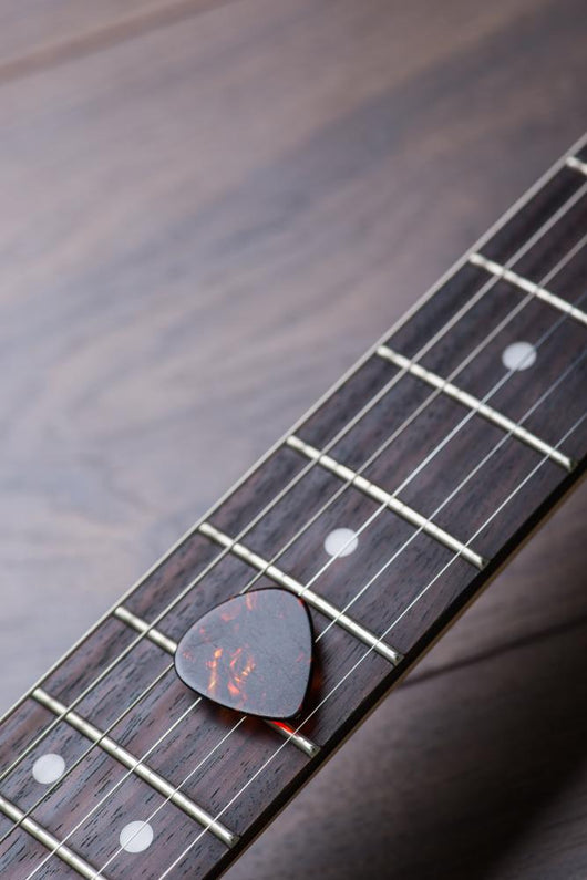 Guitar Frets With Strings And Mediator On Dark Brown Surface Wall Decal