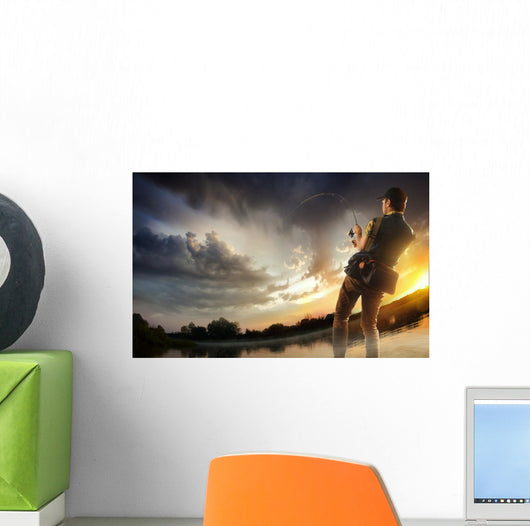 Young man fishing at dramatic sunset Wall Mural