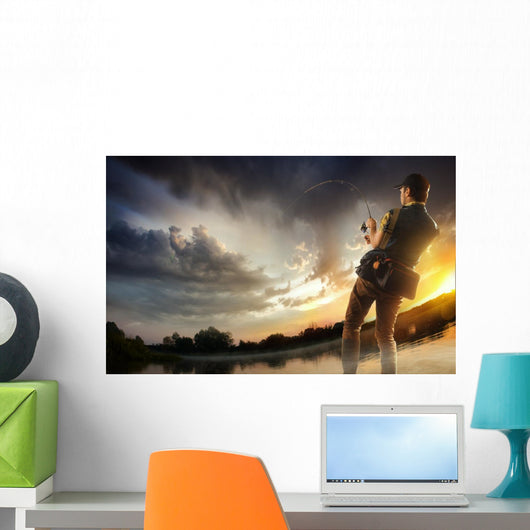 Young man fishing at dramatic sunset Wall Mural