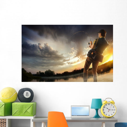 Young man fishing at dramatic sunset Wall Mural