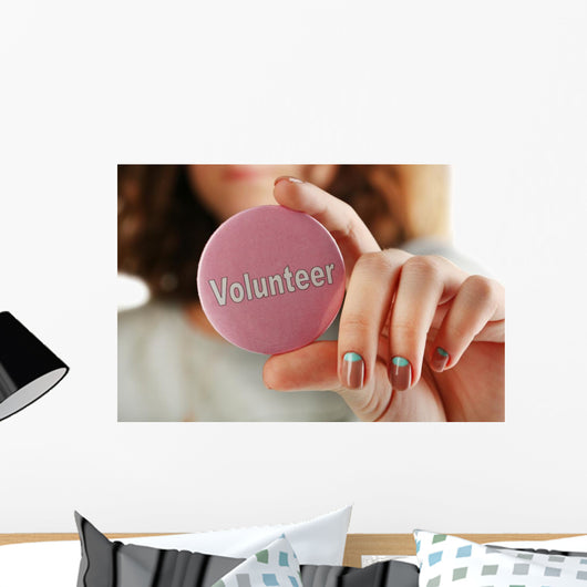 Round volunteer button in hand close-up Wall Mural