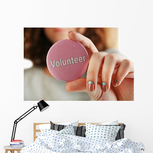 Round volunteer button in hand close-up Wall Mural