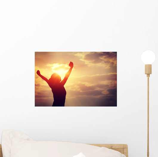 cheering woman open arms at sunrise seaside Wall Mural
